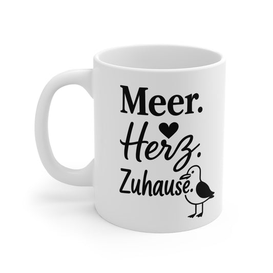 Weiße Keramiktasse mit Herzsymbol, Möwe und dem Spruch „Meer. Herz. Zuhause.“