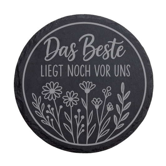 Runder schwarzer Schiefer-Untersetzer mit Gravur „Das Beste liegt noch vor uns“ im floralen Kreisdesign