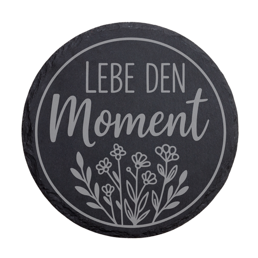 Runder schwarzer Schiefer-Untersetzer mit Gravur „Lebe den Moment“ und Blumenmotiv im Kreis