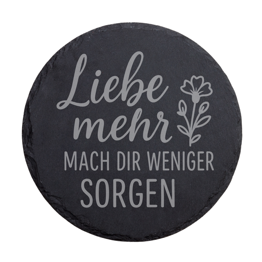 Runder schwarzer Schiefer-Untersetzer mit Gravur „Liebe mehr, mach dir weniger Sorgen“ mit Blumenmotiv