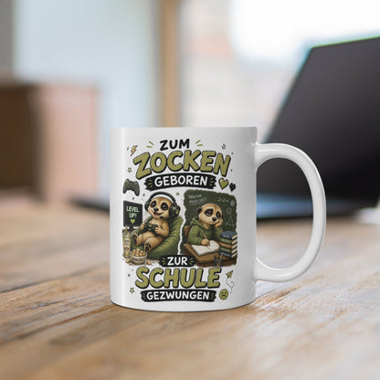 Weiße Tasse mit süßem Erdmännchen beim Gaming mit Headset, Controller und Snacks sowie Schulmotiv im Hintergrund