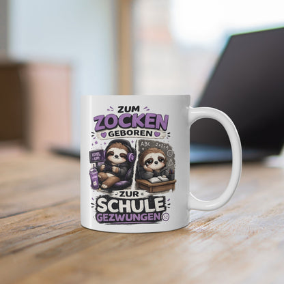 Weiße Tasse mit Faultier Gaming Motiv, Controller, Headset und humorvollem Schul Spruch auf einem Holztisch