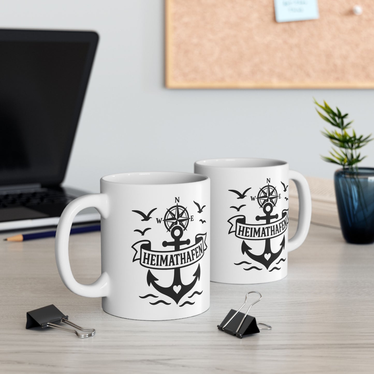 Weiße Tasse mit Anker, Kompassrose und Heimathafen Schriftzug auf Holztisch