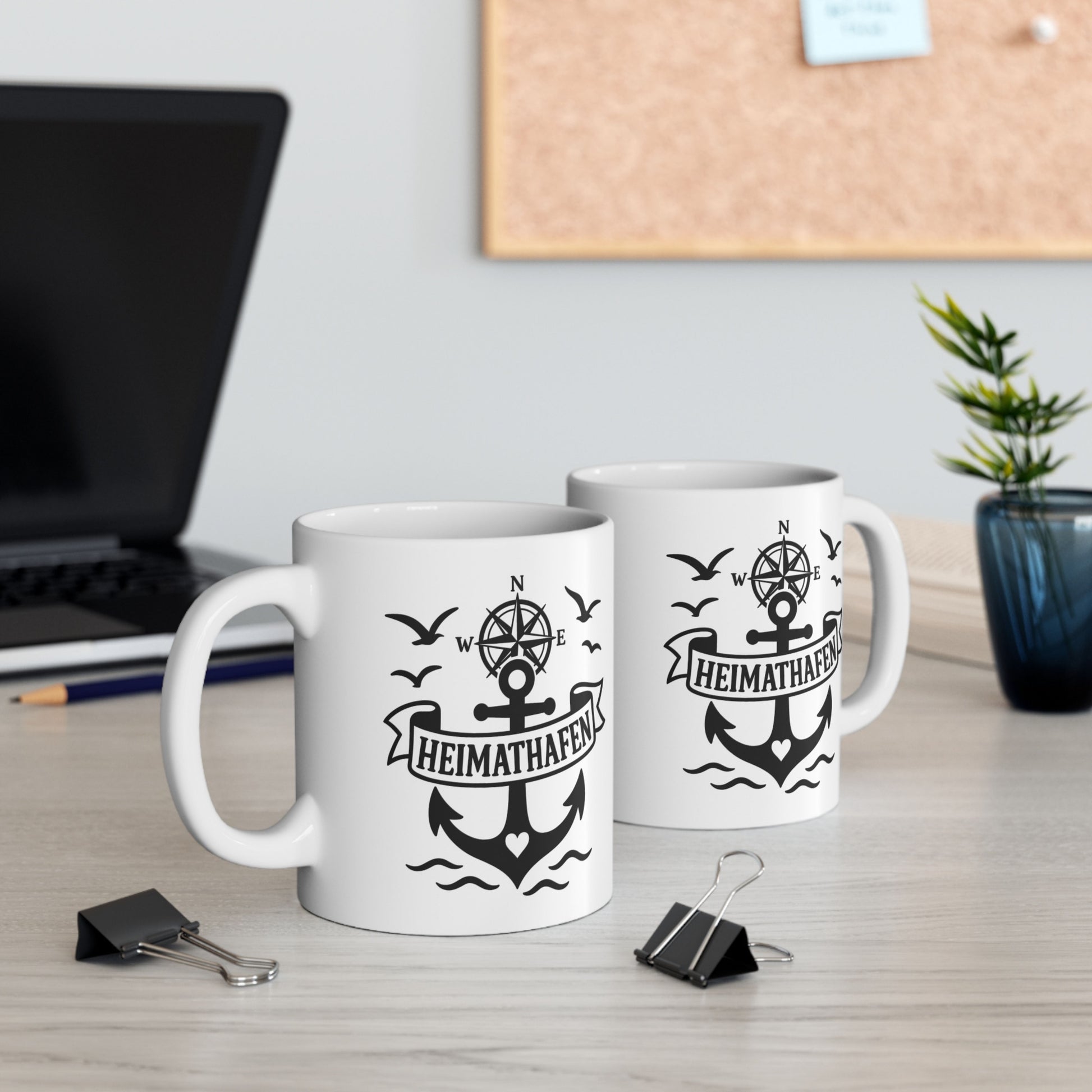 Weiße Tasse mit Anker, Kompassrose und Heimathafen Schriftzug auf Holztisch