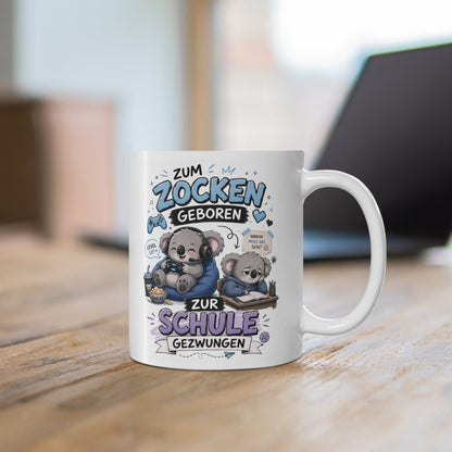Weiße Tasse mit süßem Koala beim Gaming mit Controller, Headset und humorvollem Schul Spruch auf einem Holztisch