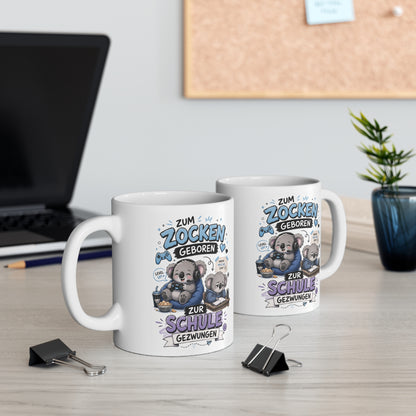 Zwei weiße Keramiktassen mit lustigem Koala Gamer Motiv und dem Spruch „Zum Zocken geboren zur Schule gezwungen“ auf einem Schreibtisch