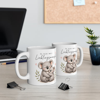 Zwei weiße Keramiktassen mit Koala-Motiv und dem Spruch „Du bist mein Lieblingsmensch“ auf einem Schreibtisch neben Laptop und Pflanze