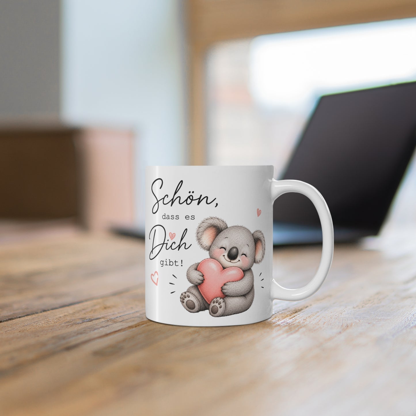 Weiße Tasse mit niedlichem Koala und rosa Herz sowie dem Schriftzug „Schön, dass es Dich gibt!“ auf einem Holztisch
