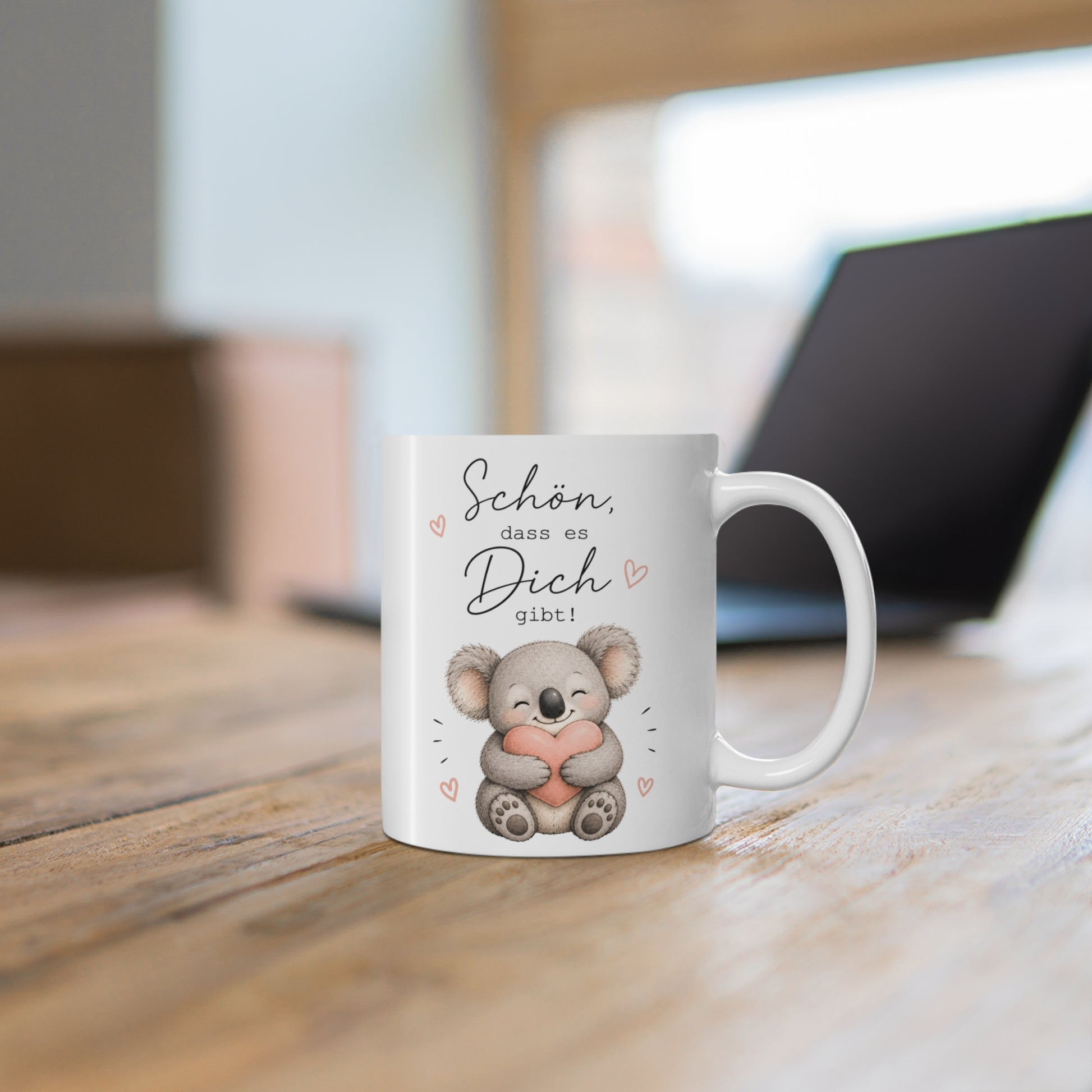 Weiße Tasse mit niedlichem Koala, rosa Herz und liebevoller Botschaft „Schön, dass es Dich gibt!“ auf einem Holztisch
