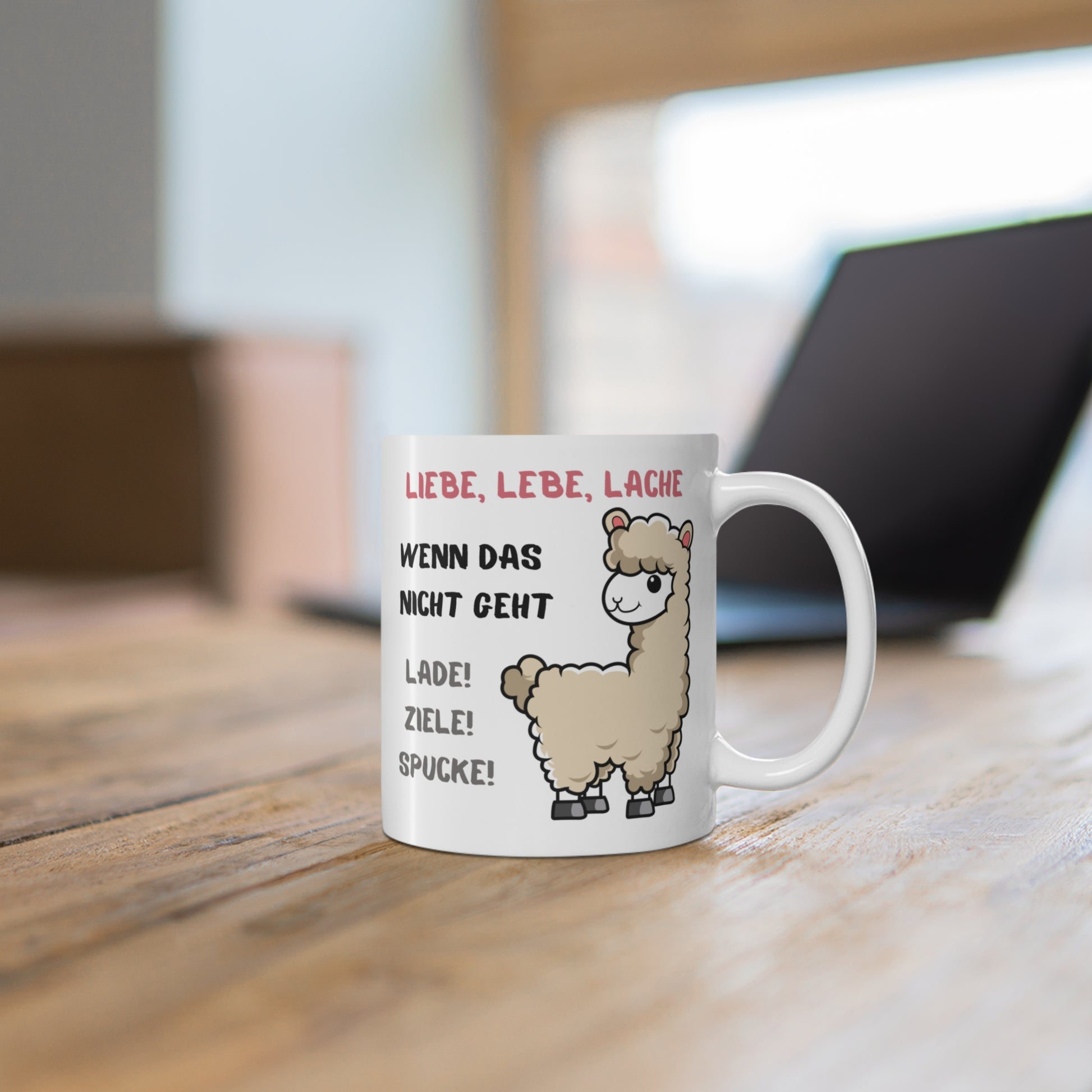 Weiße Alpaka Tasse mit humorvollem Spruch auf Holztisch vor unscharfem Hintergrund im Homeoffice