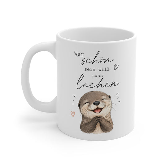 Weiße Keramiktasse mit lachendem Otter und dem Spruch „Wer schön sein will muss lachen“