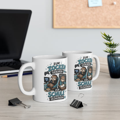 Zwei weiße Keramiktassen mit blauem Otter Gamer Motiv und Spruch „Zum Zocken geboren zur Schule gezwungen“ auf modernem Schreibtisch