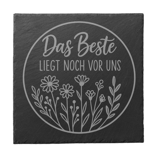 Quadratischer schwarzer Schiefer-Untersetzer mit Gravur „Das Beste liegt noch vor uns“ im Kreisdesign mit Blumenmotiv