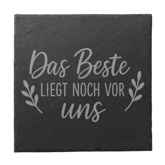 Quadratischer schwarzer Schiefer-Untersetzer mit Gravur „Das Beste liegt noch vor uns“ und dekorativen Blätterranken