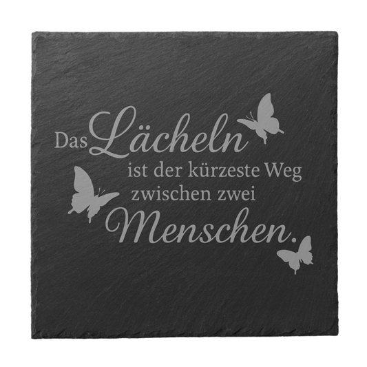 Quadratischer schwarzer Schiefer-Untersetzer mit Gravur „Das Lächeln ist der kürzeste Weg zwischen zwei Menschen“ und Schmetterlingen