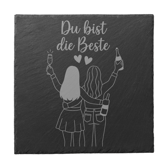 Quadratischer schwarzer Schiefer-Untersetzer mit Gravur „Du bist die Beste“ und zwei Freundinnen mit Sektgläsern