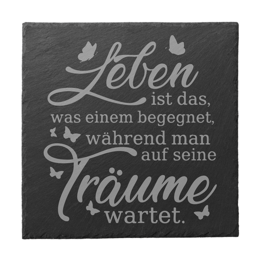 Quadratischer schwarzer Schiefer-Untersetzer mit Gravur „Leben ist das, was einem begegnet, während man auf seine Träume wartet“