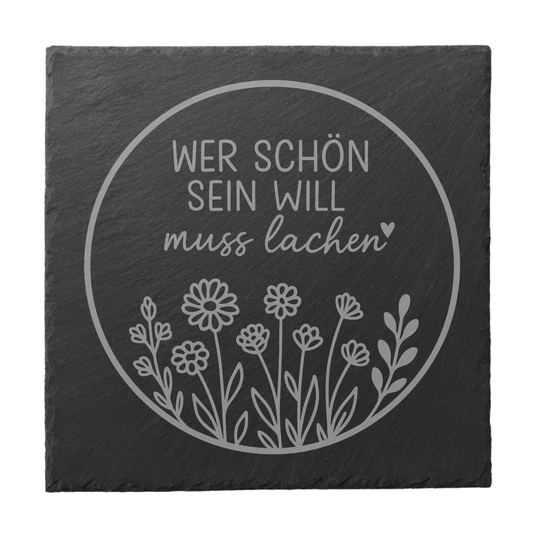 Quadratischer schwarzer Schiefer-Untersetzer mit Gravur „Wer schön sein will muss lachen“ im Kreisdesign mit Blumenmotiv