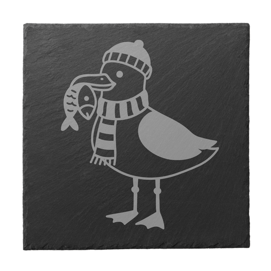 Quadratischer schwarzer Schiefer-Untersetzer mit Gravur einer Möwe mit Mütze, Schal und Fisch
