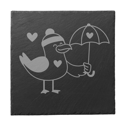 Quadratischer schwarzer Schiefer-Untersetzer mit Gravur einer Möwe mit Mütze und Herz-Regenschirm
