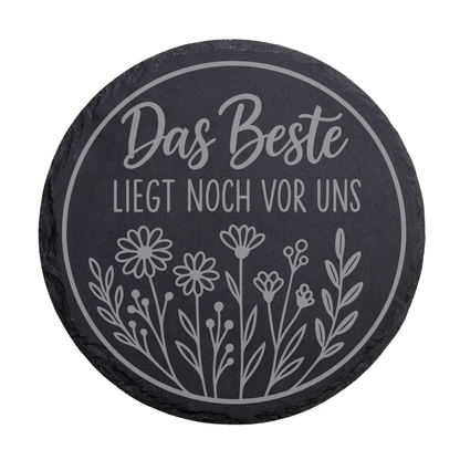 Runder schwarzer Schiefer-Untersetzer mit Gravur „Das Beste liegt noch vor uns“ im floralen Kreisdesign