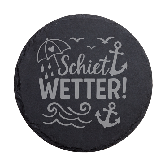 Runder schwarzer Schiefer-Untersetzer mit Schriftzug „Schietwetter!“ und norddeutschem Küstenmotiv