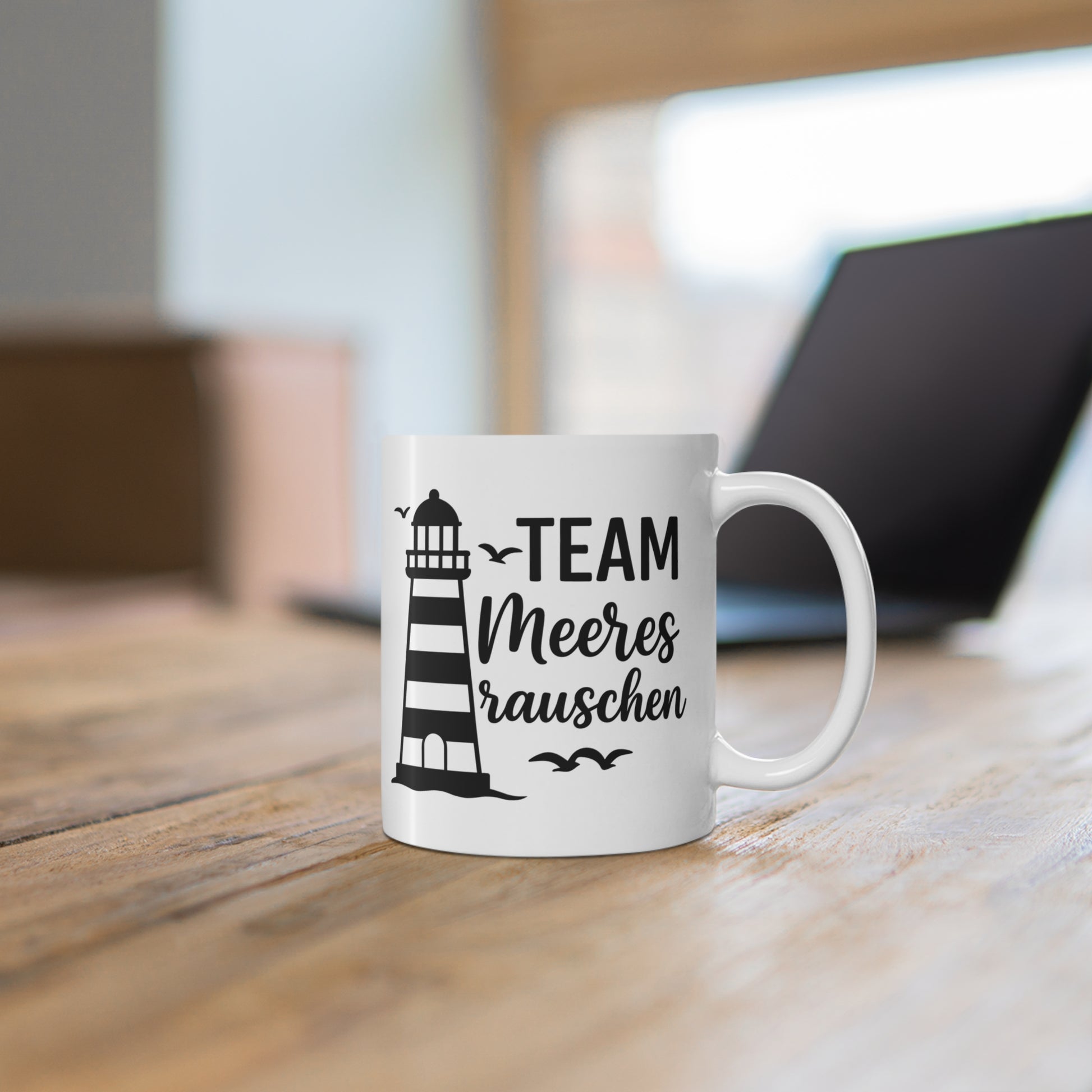Maritime Tasse mit Leuchtturm, Möwen und Schriftzug „Team Meeresrauschen“ auf einem Holztisch