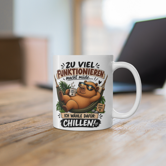 Weiße Capybara Tasse mit Sonnenbrille tragendem Capybara in Hängematte und Spruch „Zu viel Funktionieren macht müde“
