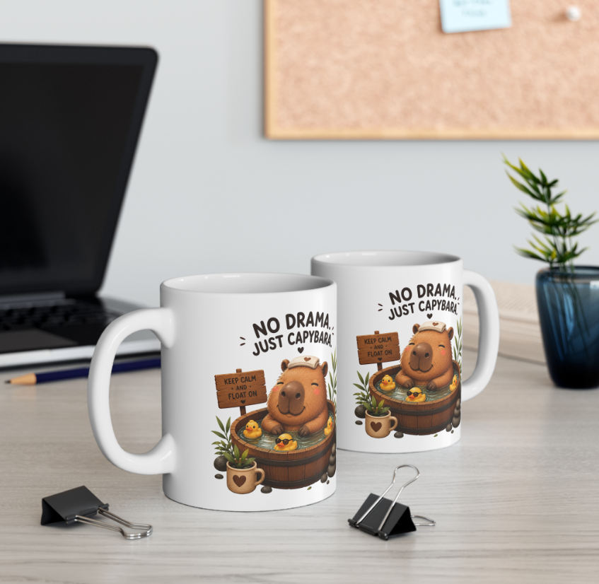 Zwei weiße Capybara Tassen mit „No Drama, Just Capybara“ Spruch und niedlichem Capybara im Badefass auf einem Schreibtisch
