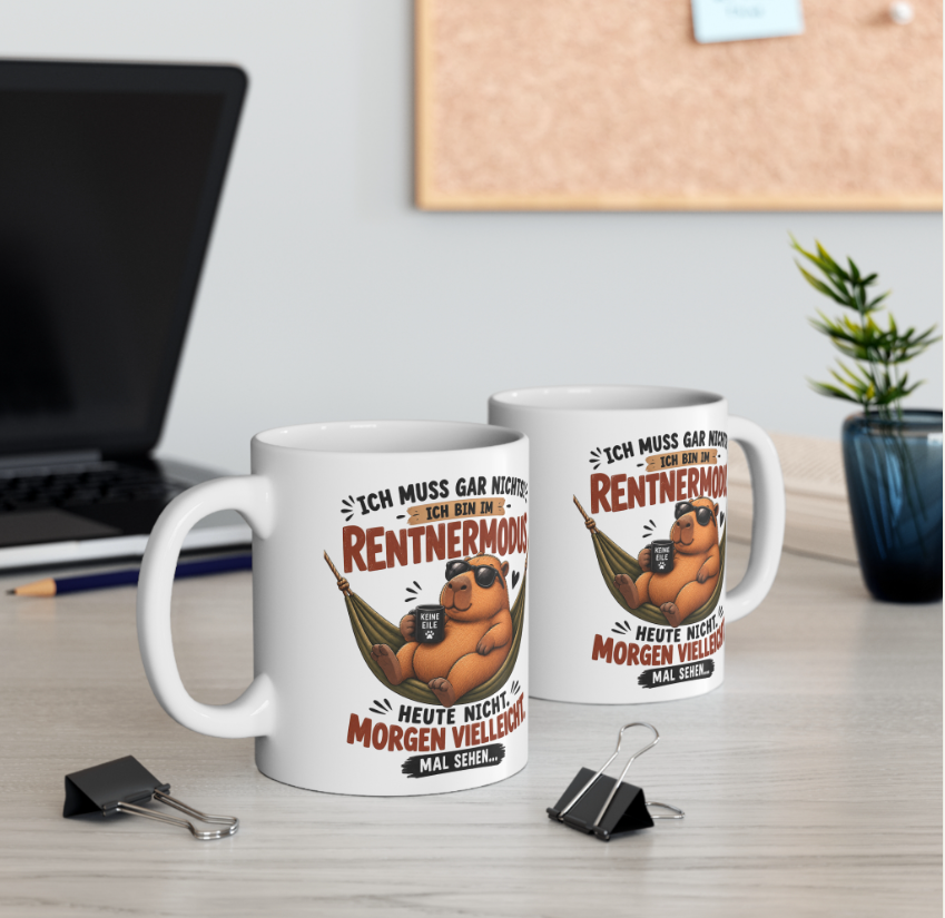 Zwei weiße Capybara Tassen mit Spruch „Ich muss gar nichts – ich bin im Rentnermodus“ auf einem Schreibtisch