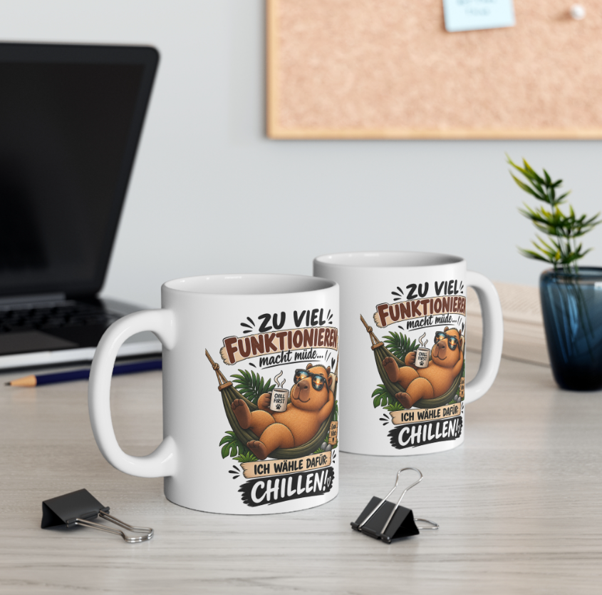 Zwei weiße Capybara Tassen mit lustigem Chillen-Spruch und Capybara in Hängematte auf einem Schreibtisch