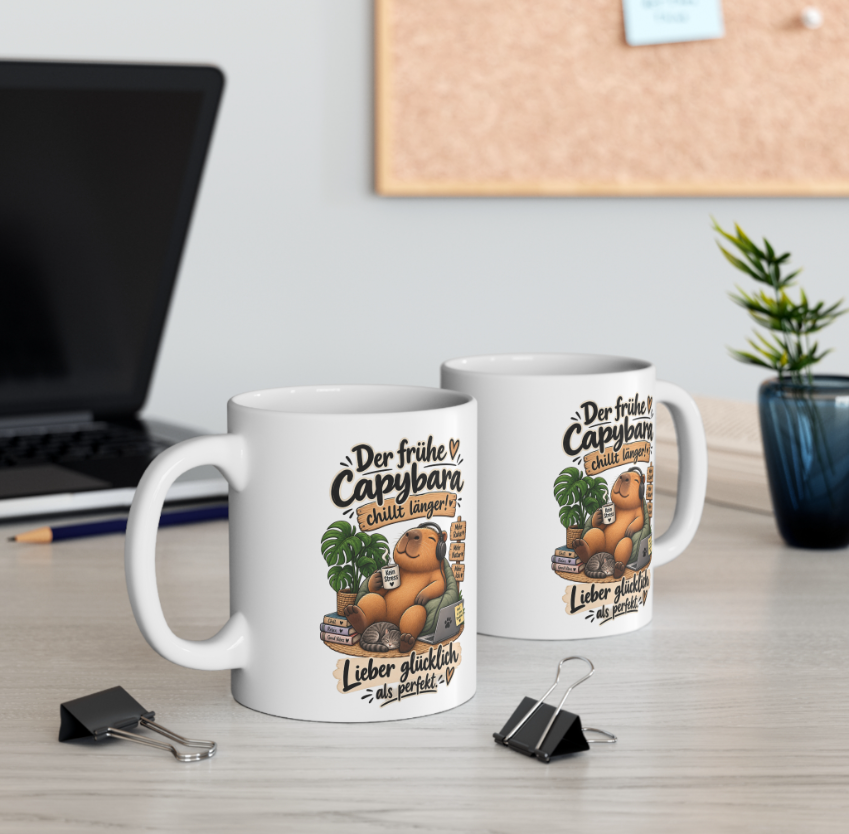 Zwei weiße Capybara Tassen mit lustigem Chillen-Spruch und entspanntem Capybara mit Kopfhörern auf einem Schreibtisch