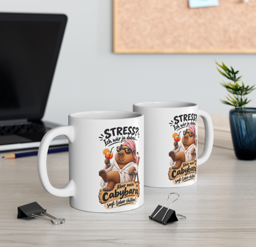 Zwei weiße Capybara Tassen mit lustigem Stress Spruch als Geschenkidee auf einem Schreibtisch im Büro